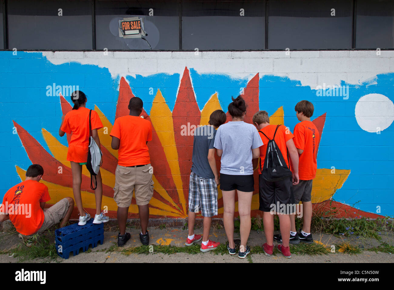 Detroit, Michigan - Alta scuola volontari vernice su un edificio vuoto. Essi stanno lavorando per tutta l'estate in città programma. Foto Stock