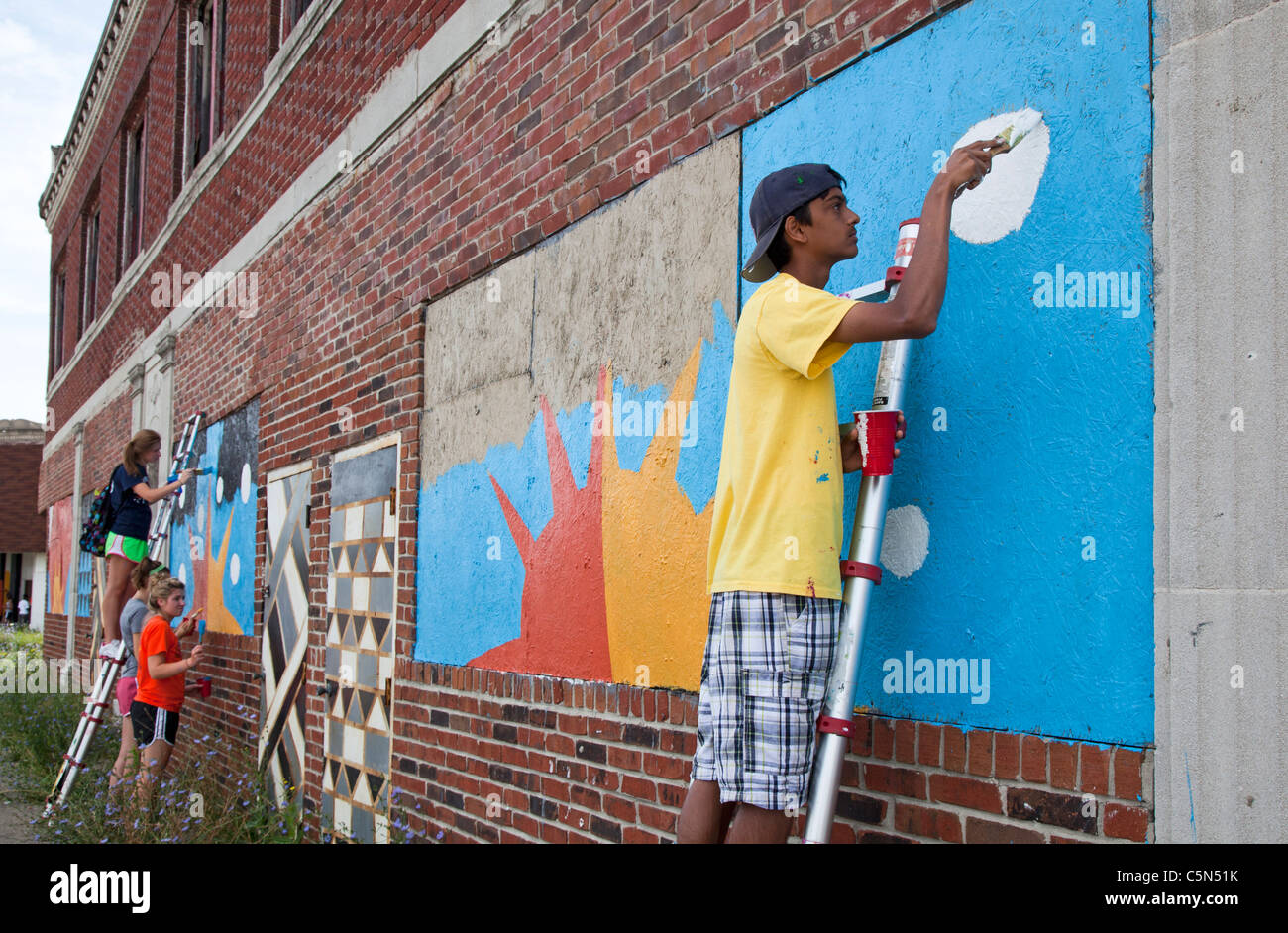 Detroit, Michigan - Alta scuola volontari vernice su un edificio vuoto. Essi stanno lavorando per tutta l'estate in città programma. Foto Stock