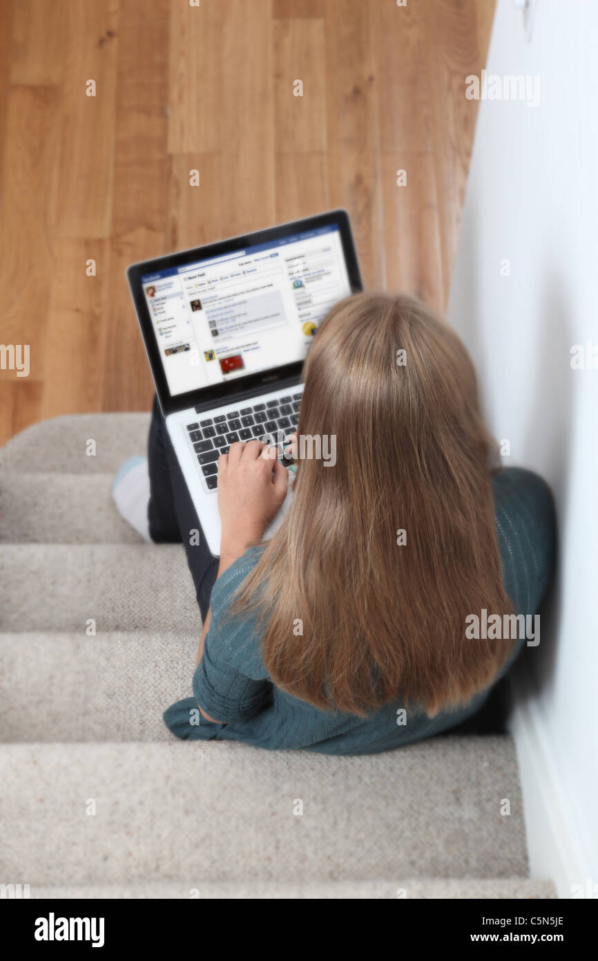 Ragazza giovane con laptop sulla pagina Facebook. Foto Stock