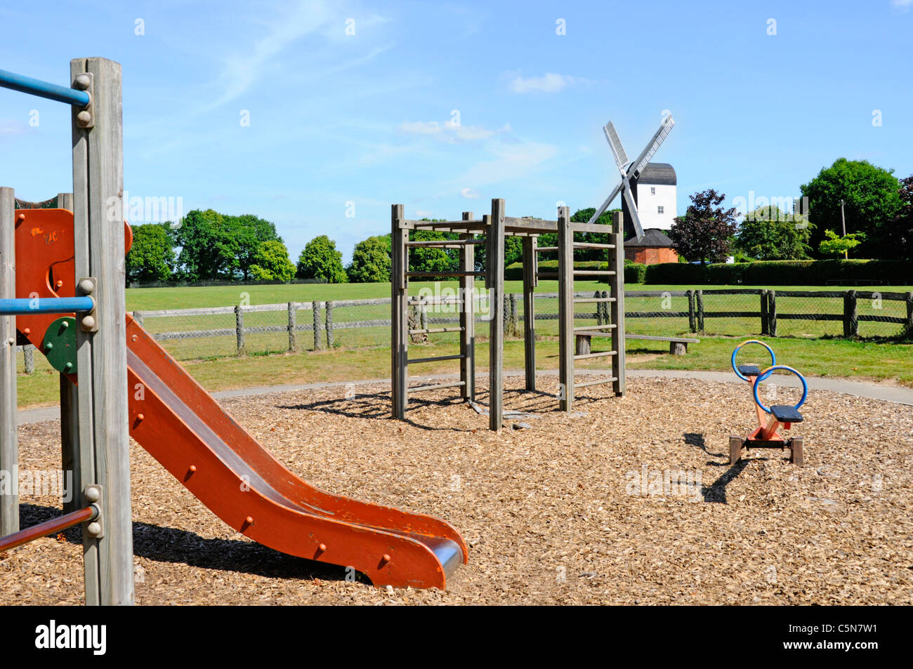 Parco giochi slide & arrampicata in frame recintata area giochi per i bambini sul verde villaggio con Mountnessing post mill windmill Brentwood Essex Inghilterra UKUK Foto Stock