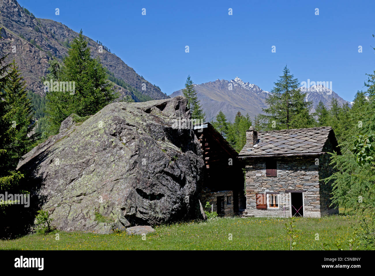 Il contrasto di una piccola casa con un enorme blocco irregolare (Italia). Amusant contraste entre une maison et onu blocco énorme erratique. Foto Stock