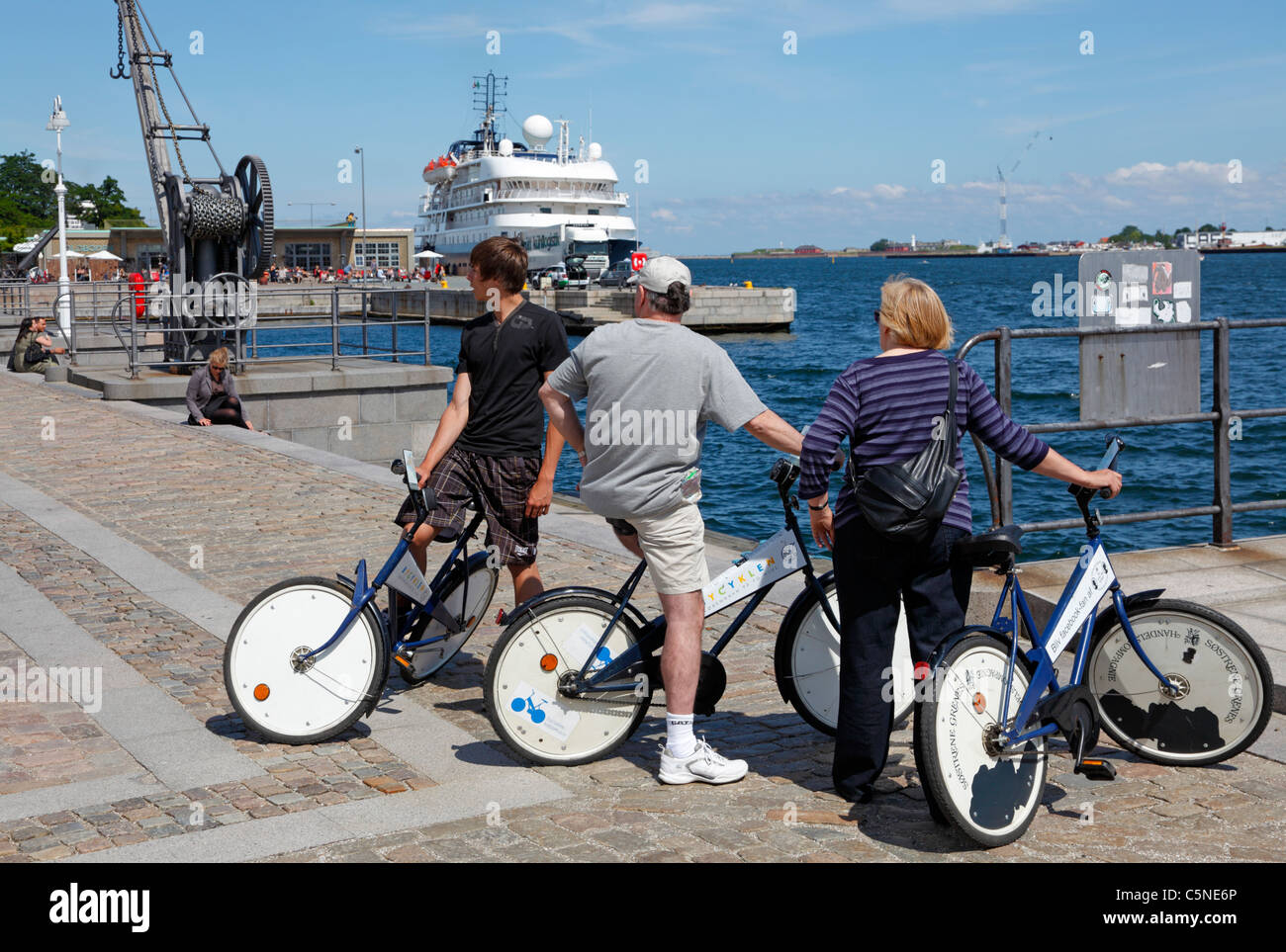 I turisti si divertano a visitare il porto di Copenhagen durante il sole d'estate in bicicletta con le Citybikes gratuite di Copenhagen. Toldboden, Copenaghen, Danimarca. Foto Stock