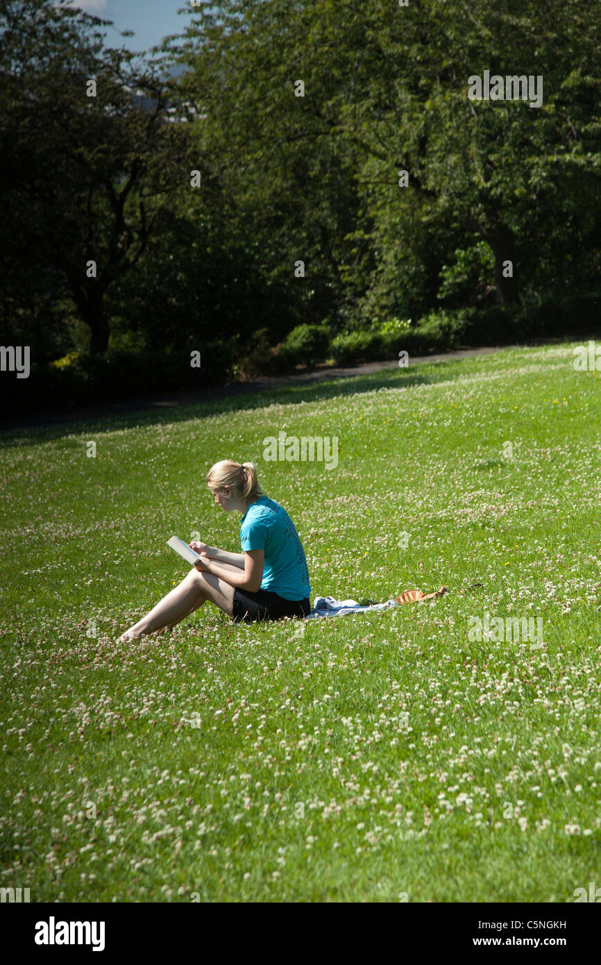 Lettura della ragazza al sole in Regent Park, Edimburgo Foto Stock