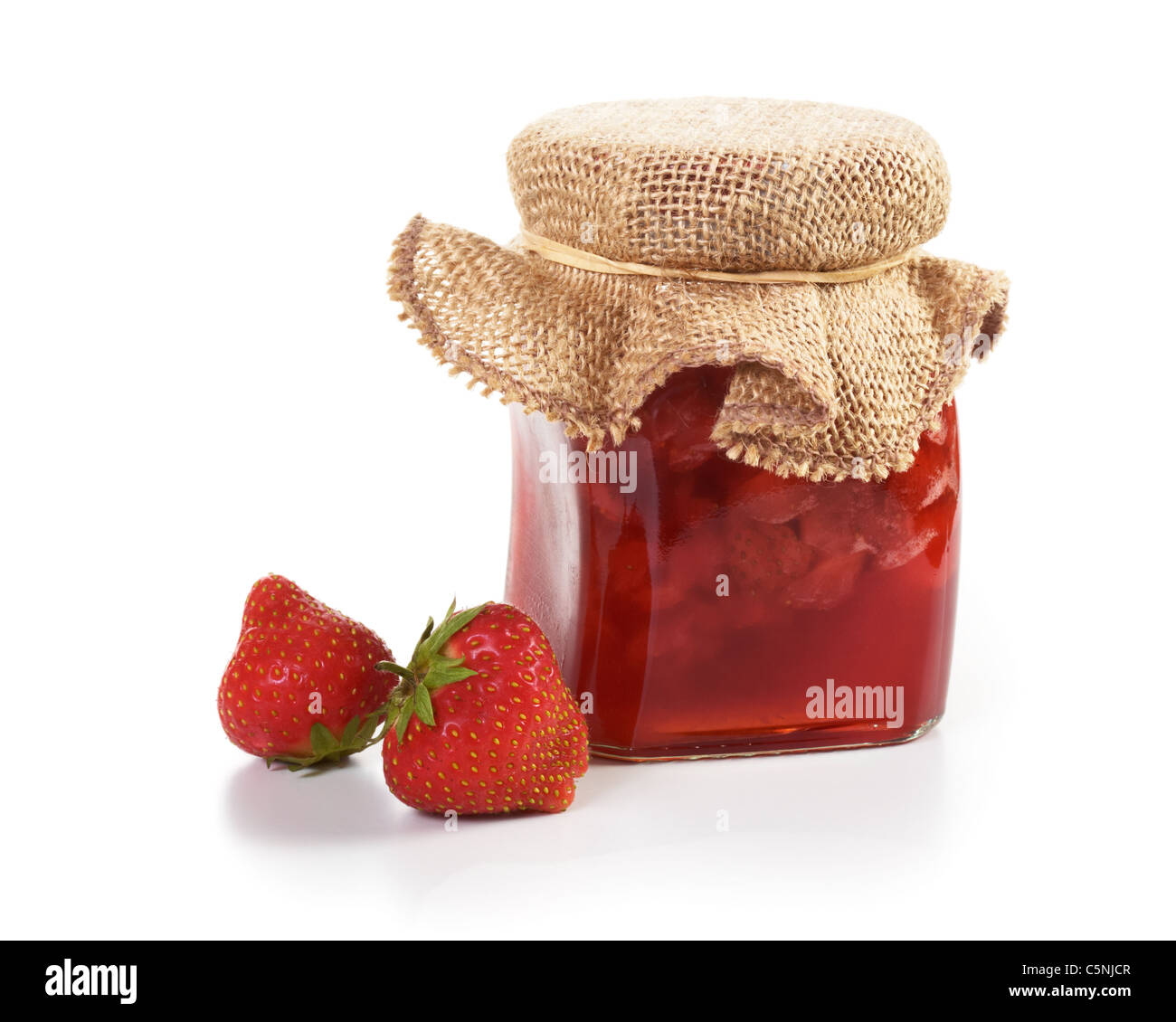 Vasetto di marmellata di fragole per dare come un dono e fragole fresche su bianco Foto Stock