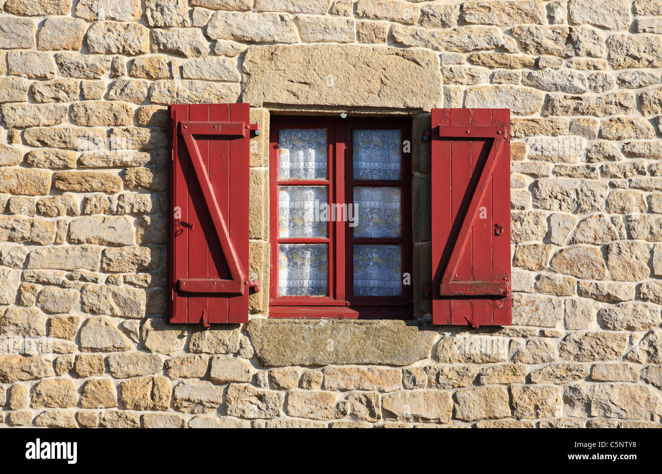 Finestra con persiane rosse sulla vecchia casa di pietra Ploemel, Bretagna Francia Foto Stock