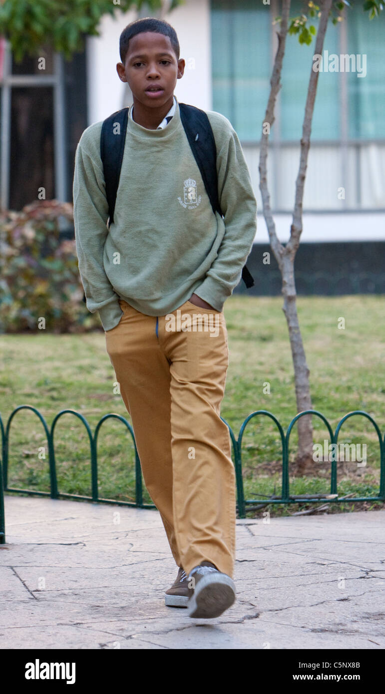 Cuba, La Habana. Cuba giovane generazione. Ragazzo adolescente andando a scuola. Ocra Gialla-pantaloni o gonne indicare scuola secondaria. Foto Stock