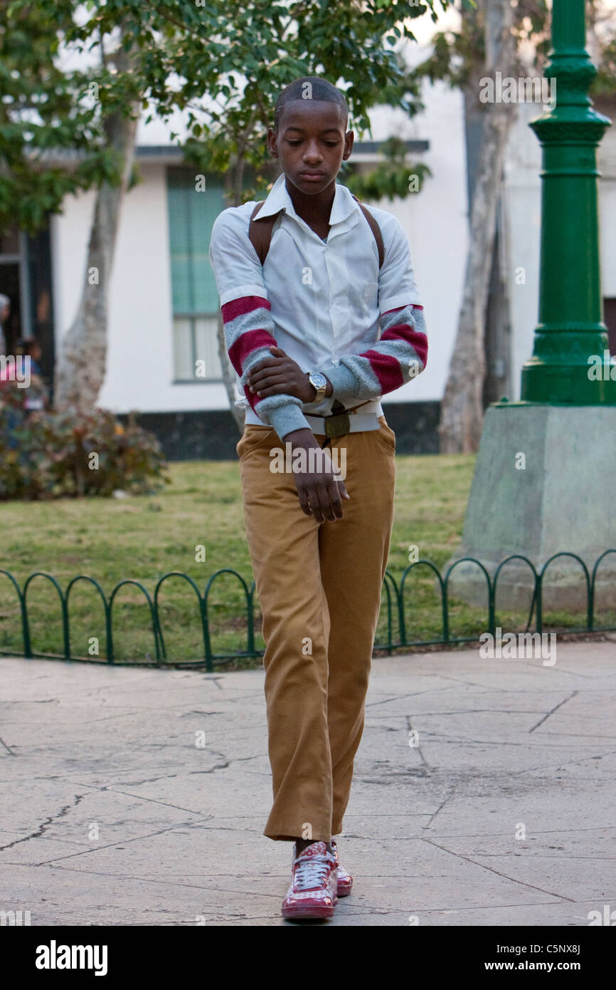 Cuba, La Habana. Cuba giovane generazione. Ragazzo adolescente andando a scuola. Ocra Gialla-pantaloni o gonne indicare scuola secondaria. Foto Stock