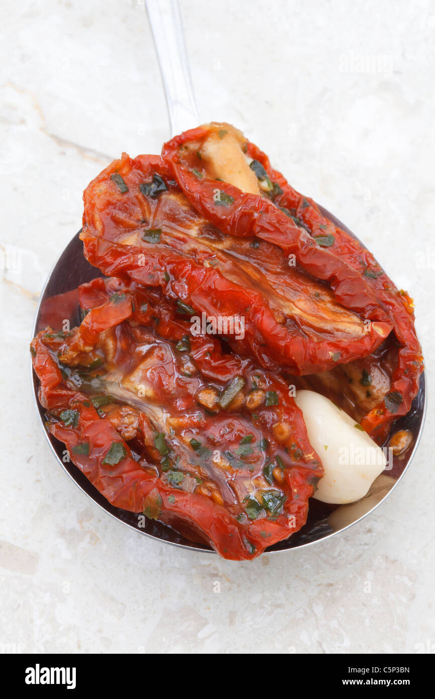 Pomodori secchi con aglio ed erbe su un cucchiaio Foto Stock