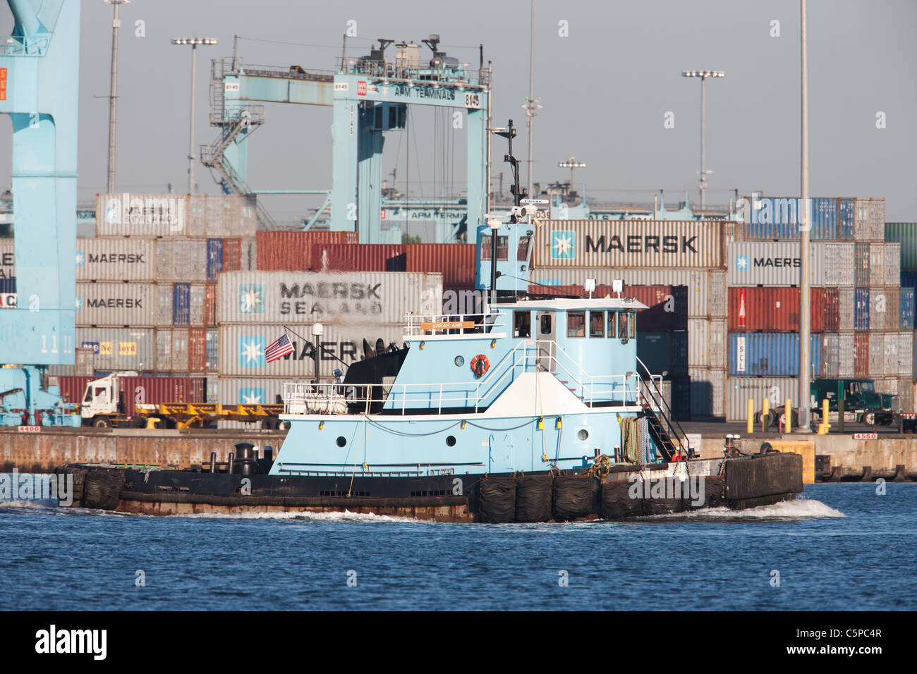 Un mastio Marine rimorchiatore passa la P.A. Moller-Maersk facility nel porto Newark-Elizabeth Terminale Marino nella baia di Newark. Foto Stock