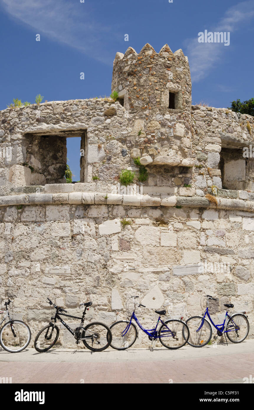 Biciclette appoggiata contro le vecchie fortificazioni facenti parte della parete della antica città di Kos, Grecia Foto Stock