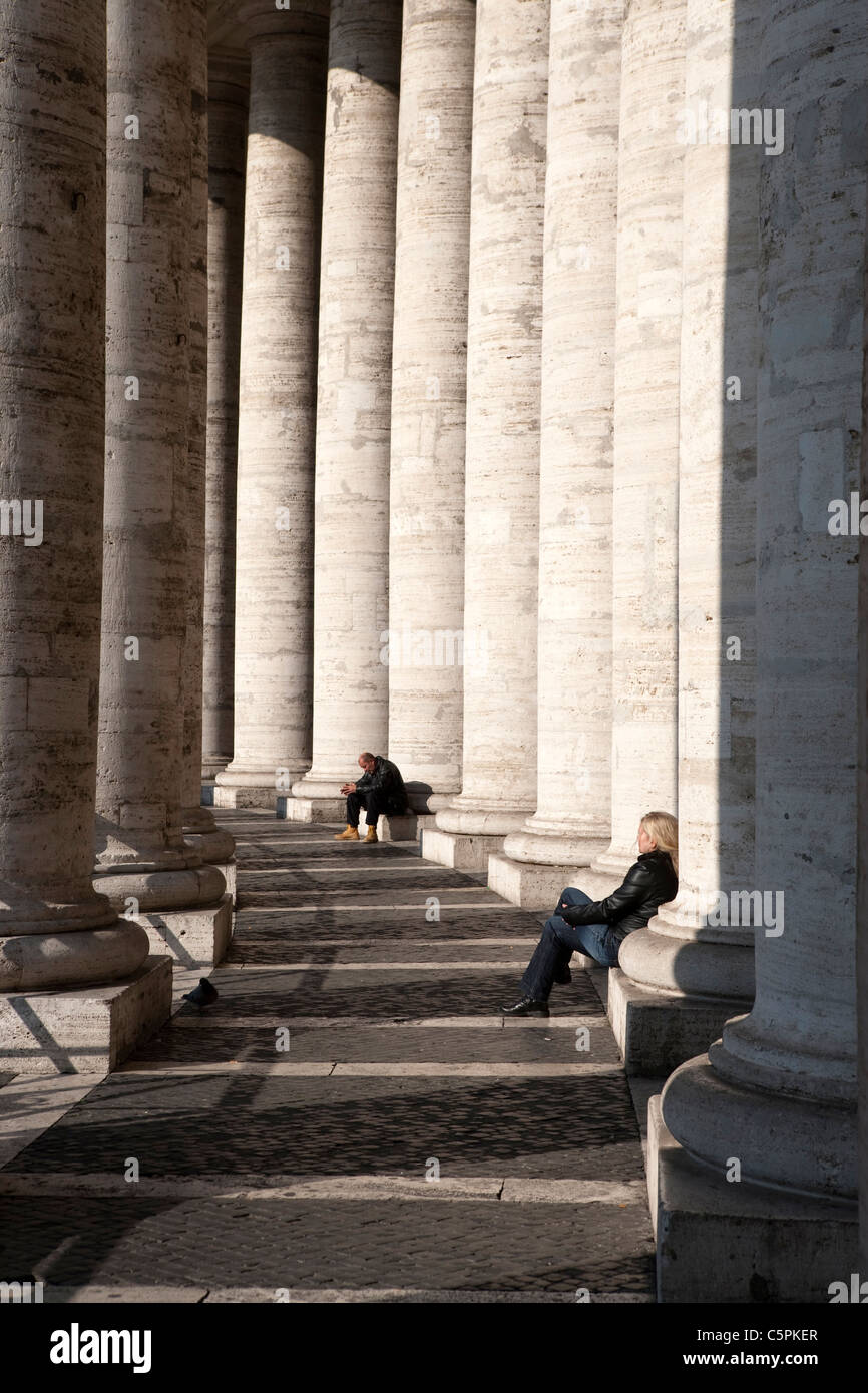 Persona seduta sotto il colonnato di Piazza San Pietro , Città del Vaticano, Roma Foto Stock