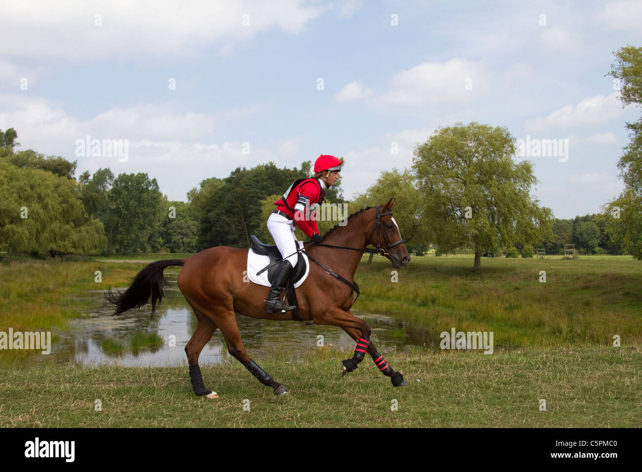 Galoppo al lago di cross country, agilità, competitivo, percorso, equitazione, equino, salto, saltare, gara, successo, competizione, galoppo, galoppante, cavallo, equitazione, mammifero, movimento, cavaliere, equitazione, spettacolo, velocità, schizzo, spruzzo, torneo, cross country, evento, cavalcata, sport, animale, campagna, erba, in movimento, natura, all'aperto, acqua, equitazione di campagna a Cholmondeley Castle, Castle Horse Trials, 2011, Cheshire, UK Foto Stock