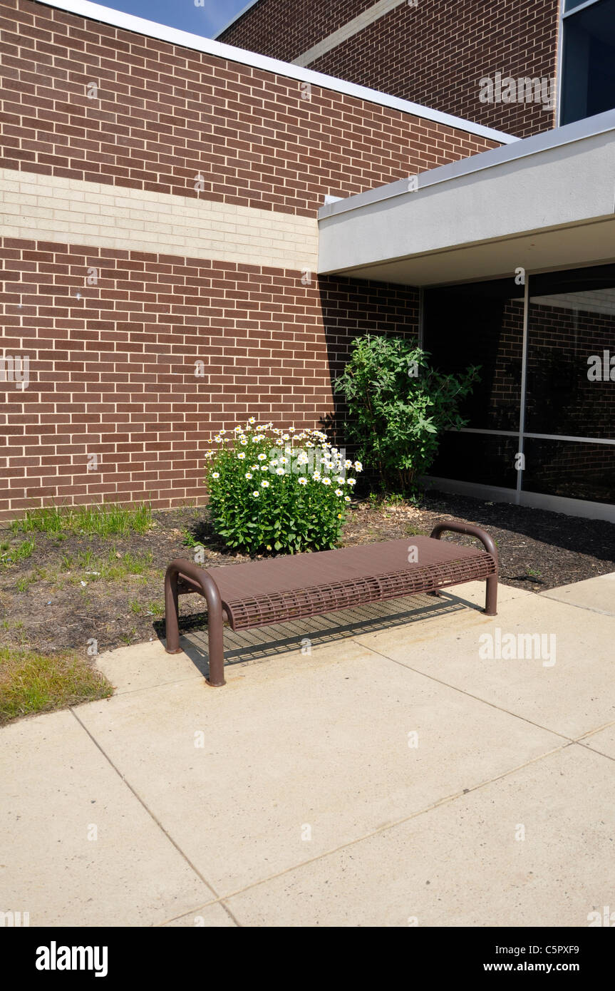 Banco vuoto al di fuori di un edificio scolastico Foto Stock