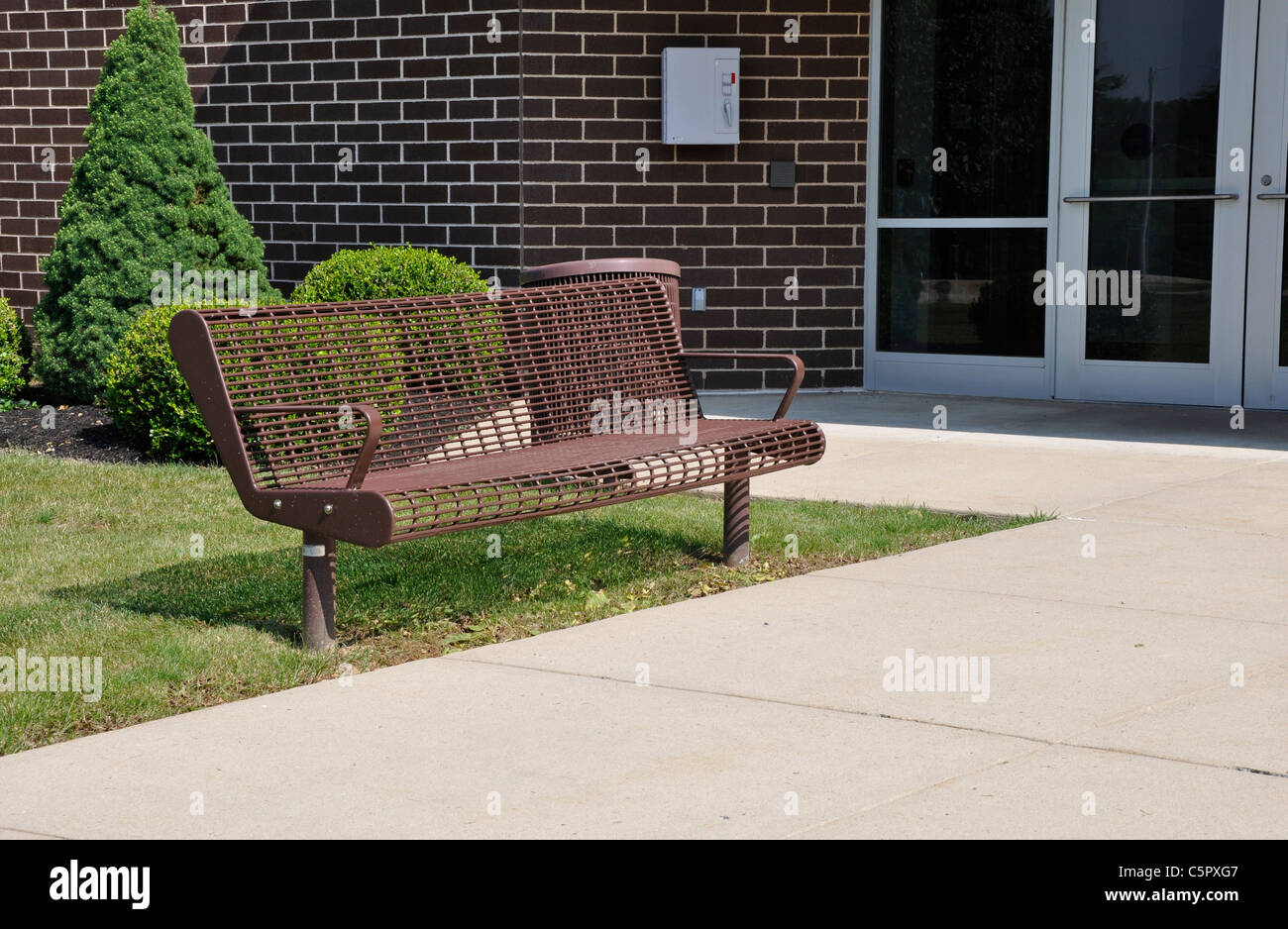 Banco vuoto al di fuori di un edificio scolastico Foto Stock