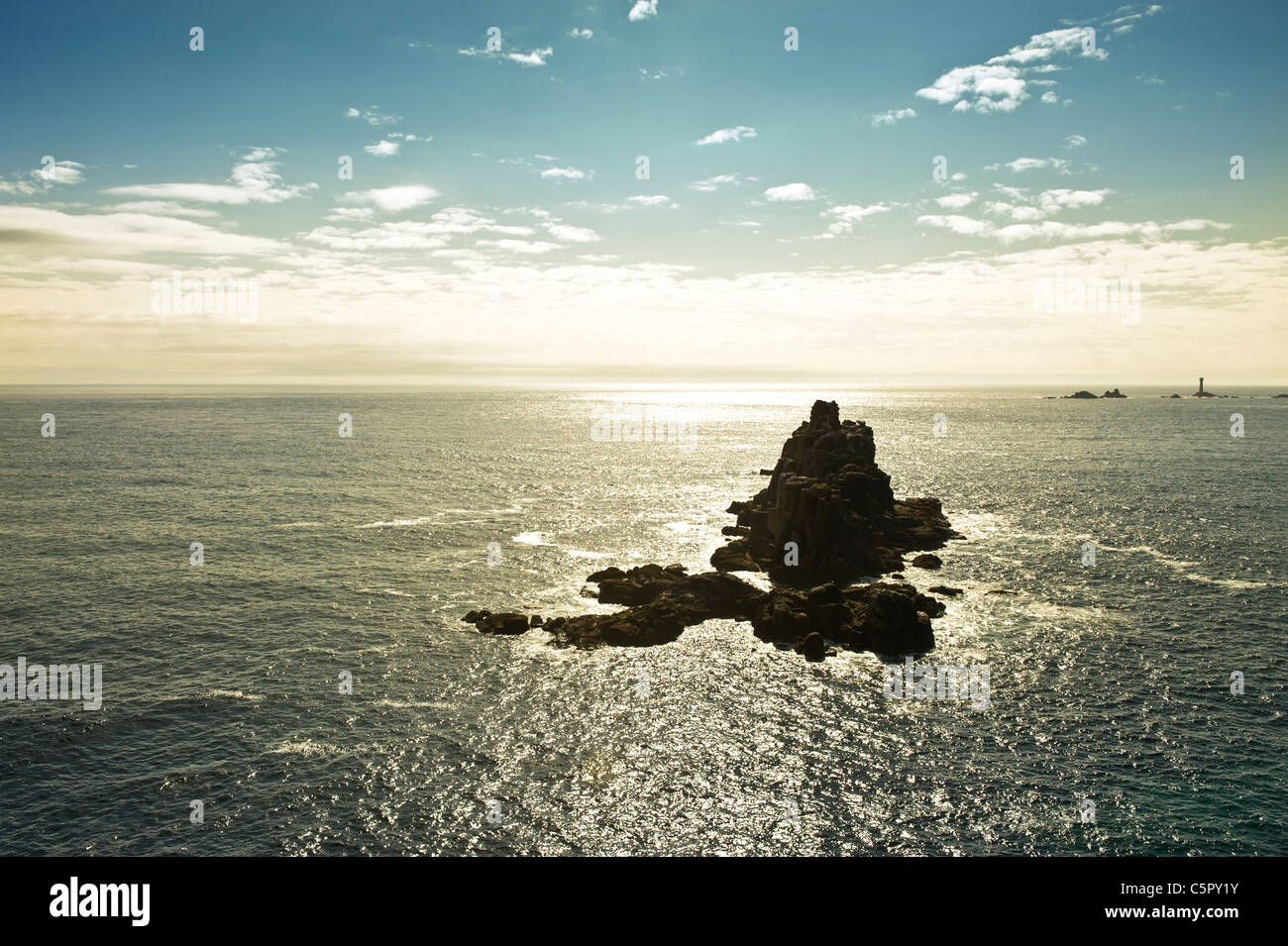 Rocce di soddisfare la lappatura di mare presso la costa di un tramonto Land's End, Cornwall. Foto Stock