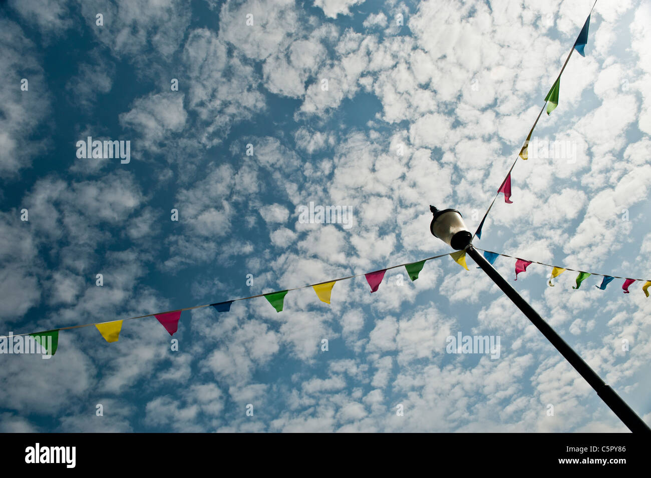 Bunting legato ad un lampione contro un lacunose cielo nuvoloso Falmouth, Cornwall. Foto Stock