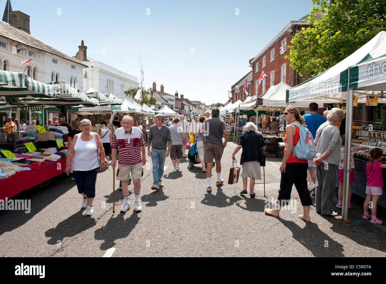 Gli amanti dello shopping passeggiata attorno a una strada del mercato di Christchuch, Dorset, in una calda giornata estiva. Foto Stock