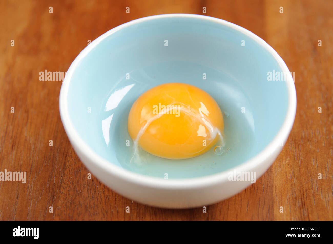 Tuorlo d'uovo crudo in una ciotola blu Foto Stock