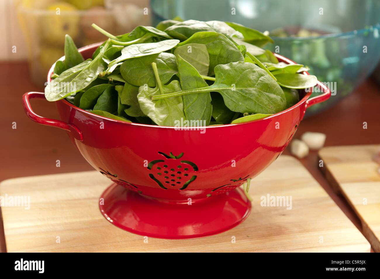 Spinaci freschi foglie di insalata durante lo scarico in un filtro rosso Foto Stock