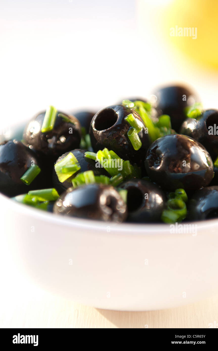 Olive nere in una ciotola bianca con erba cipollina Foto Stock