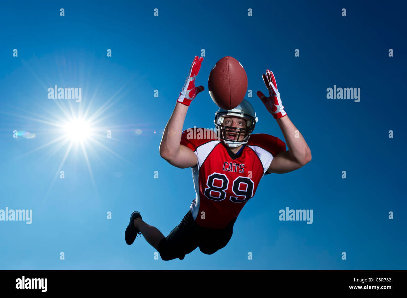Giocatore di Football Americano volare attraverso l'aria per effettuare la cattura. Foto Stock