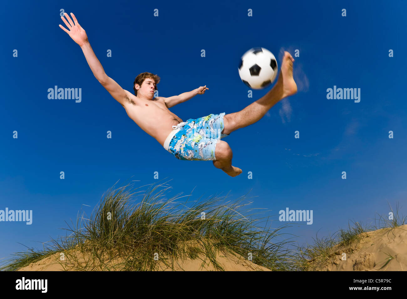 Un calcio sulla spiaggia giocatore si connette per l'overhead kick. Foto Stock