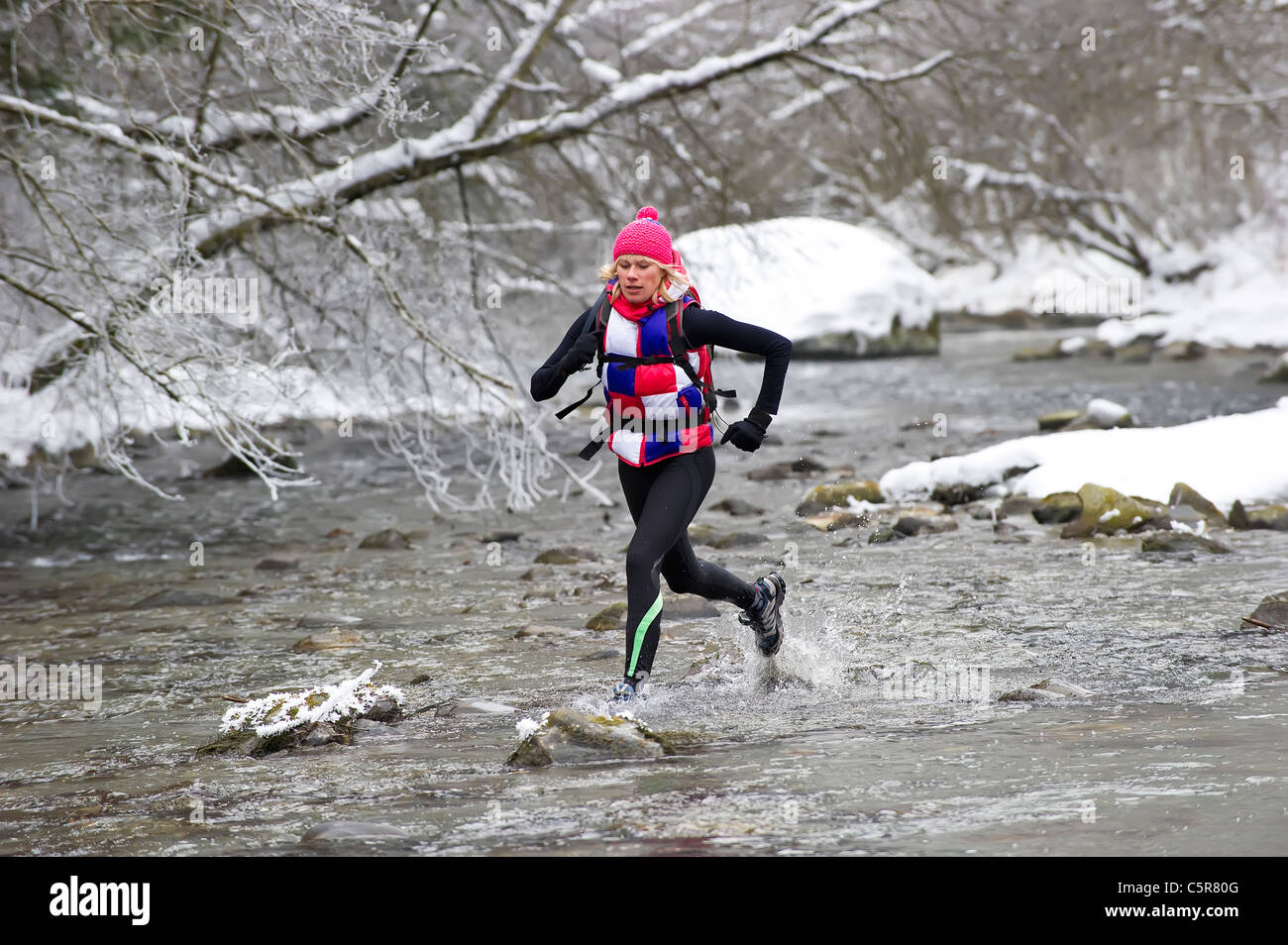 Un pareggiatore attraversando un inverno nevoso fiume. Foto Stock