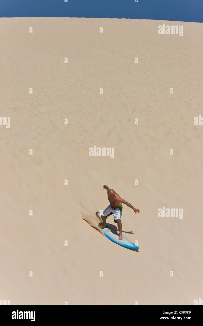 Un surfista surf un enorme duna di sabbia. Foto Stock