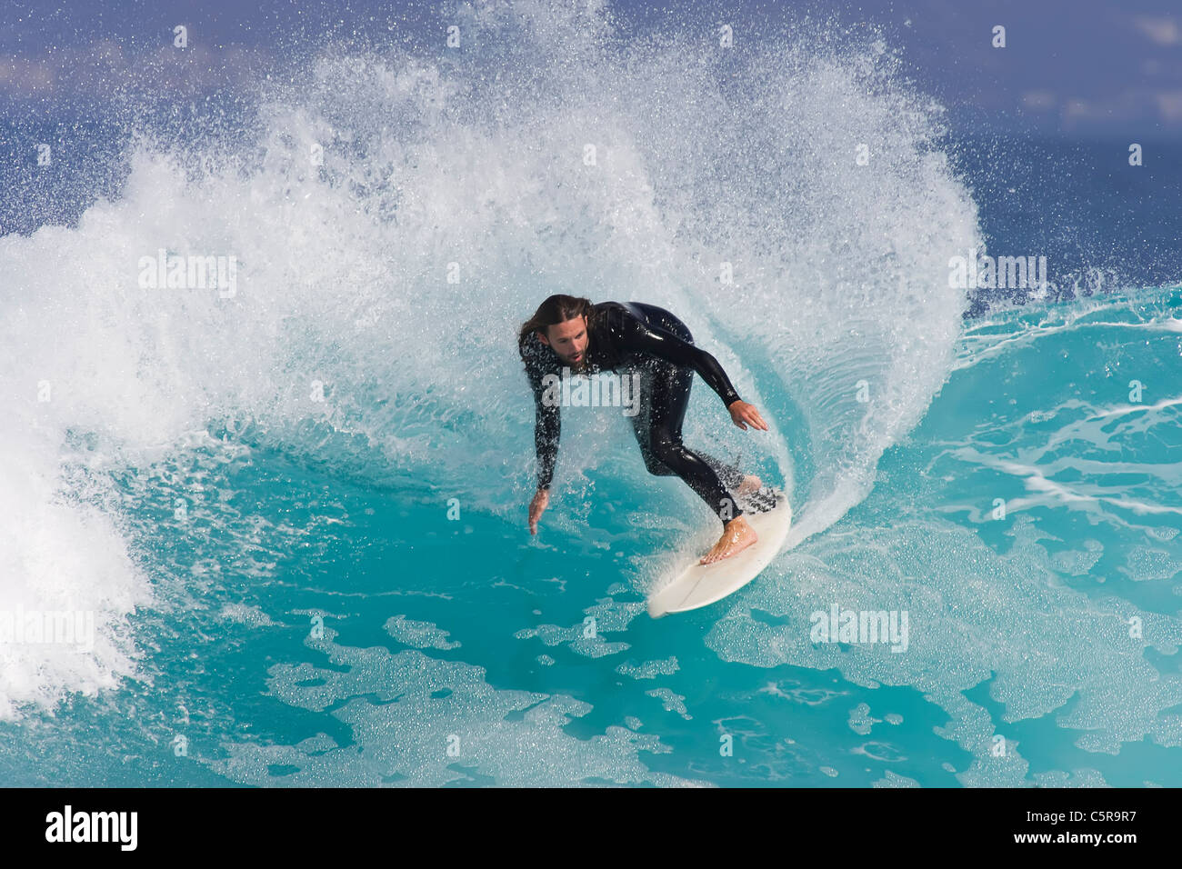 Surfer passeggiate lungo blu azzurro onda. Foto Stock