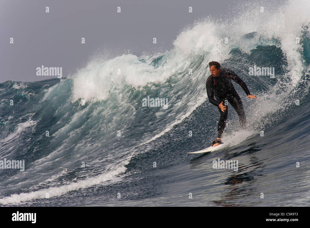 Persone di mezza età surfer in sella a una grande onda. Foto Stock