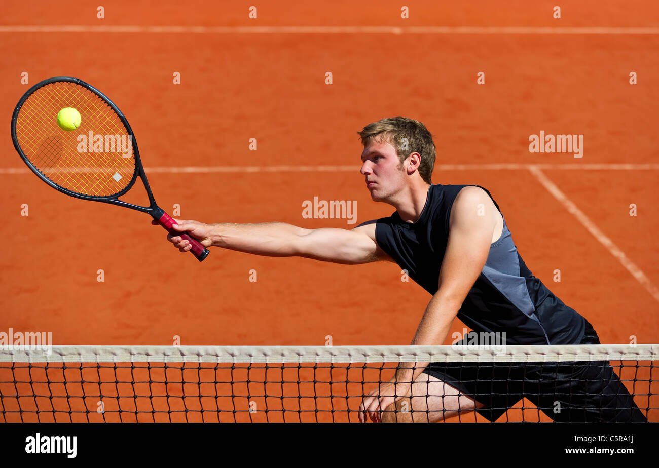 Un giocatore di tennis al netto si allunga per giocare a palla. Foto Stock