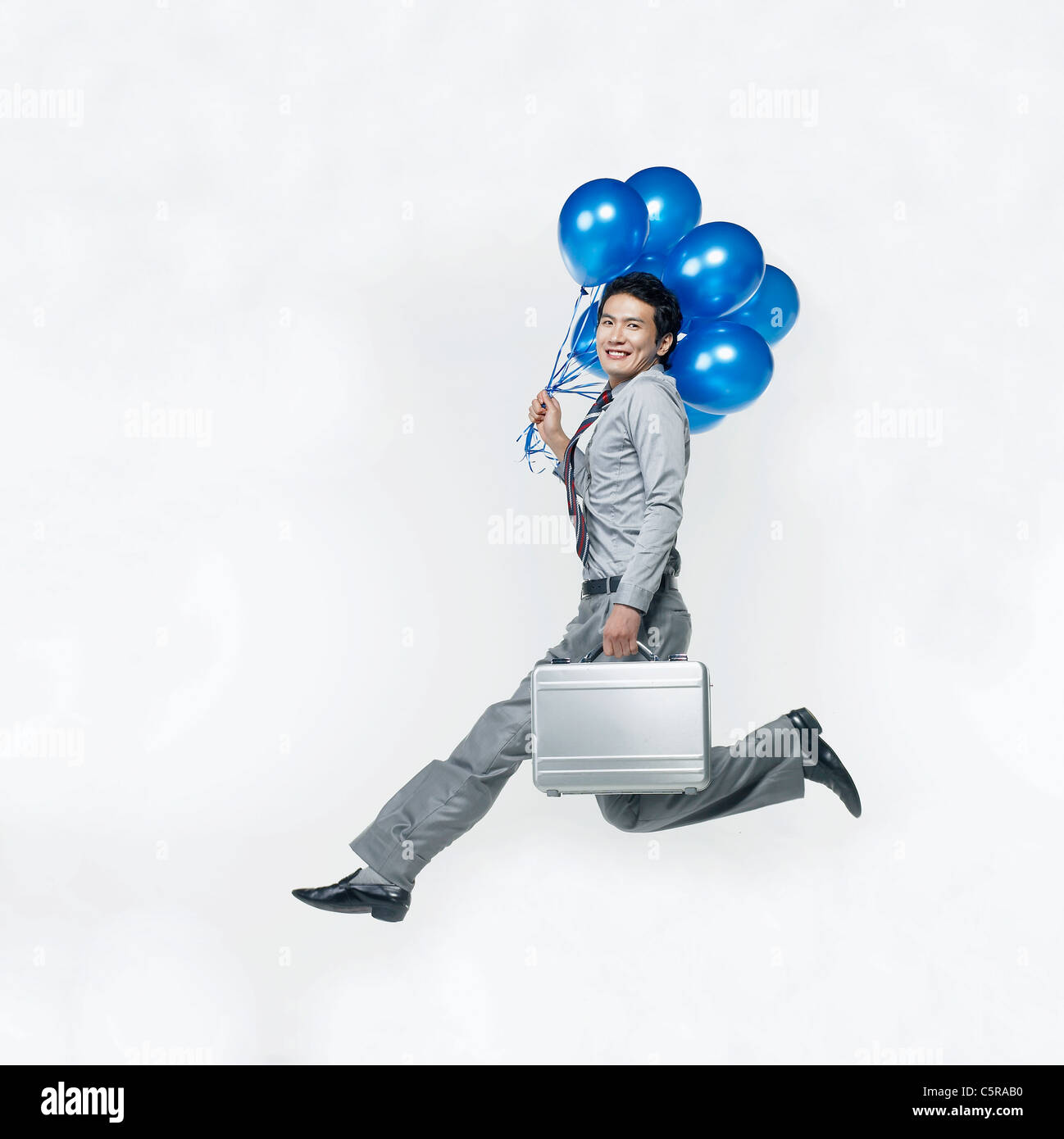 Un uomo con palloncini blu e una valigetta Foto Stock