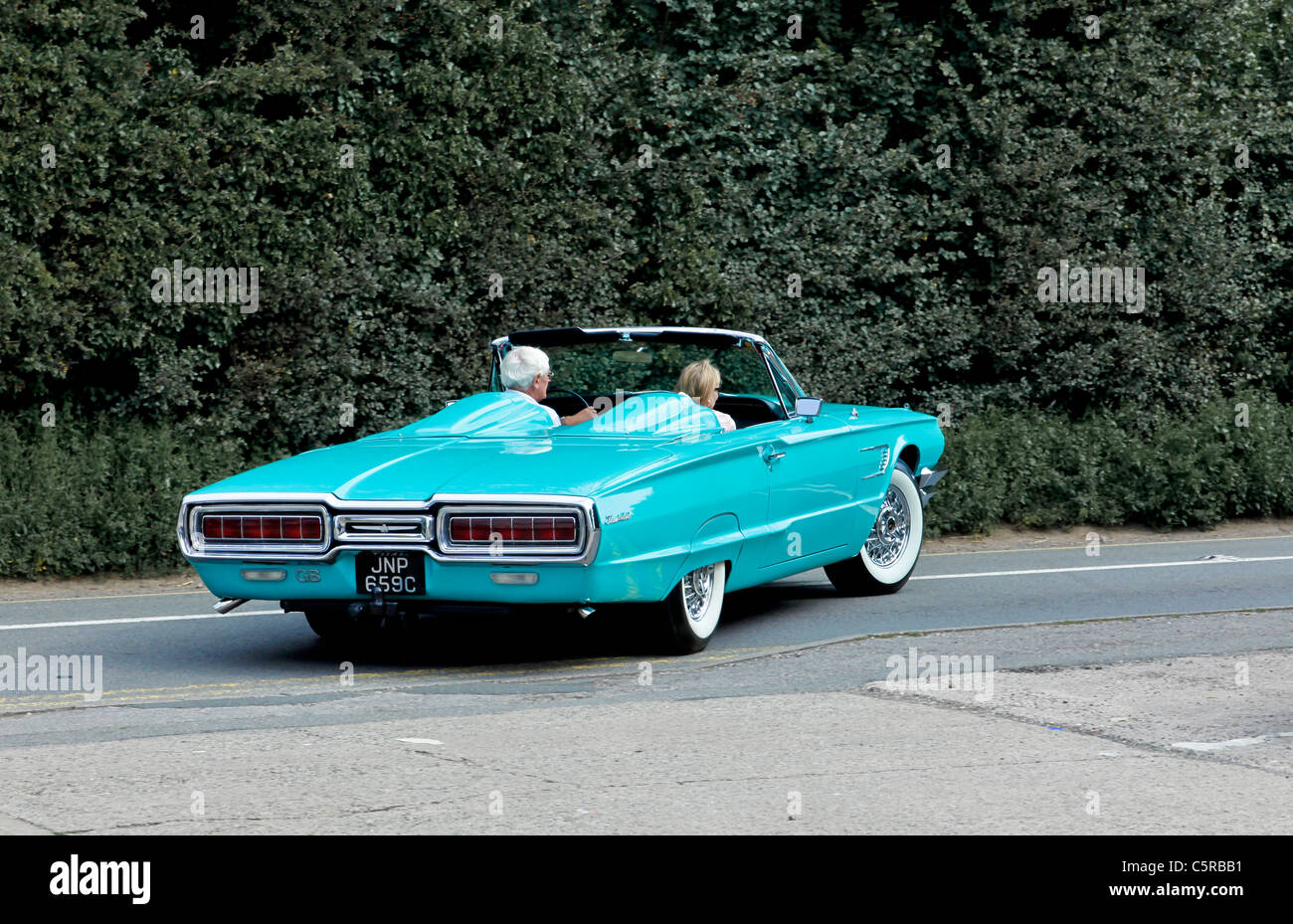 Un 1965 blu pallido Ford Thunderbird convertibile con una coppia matura la guida in esso Foto Stock