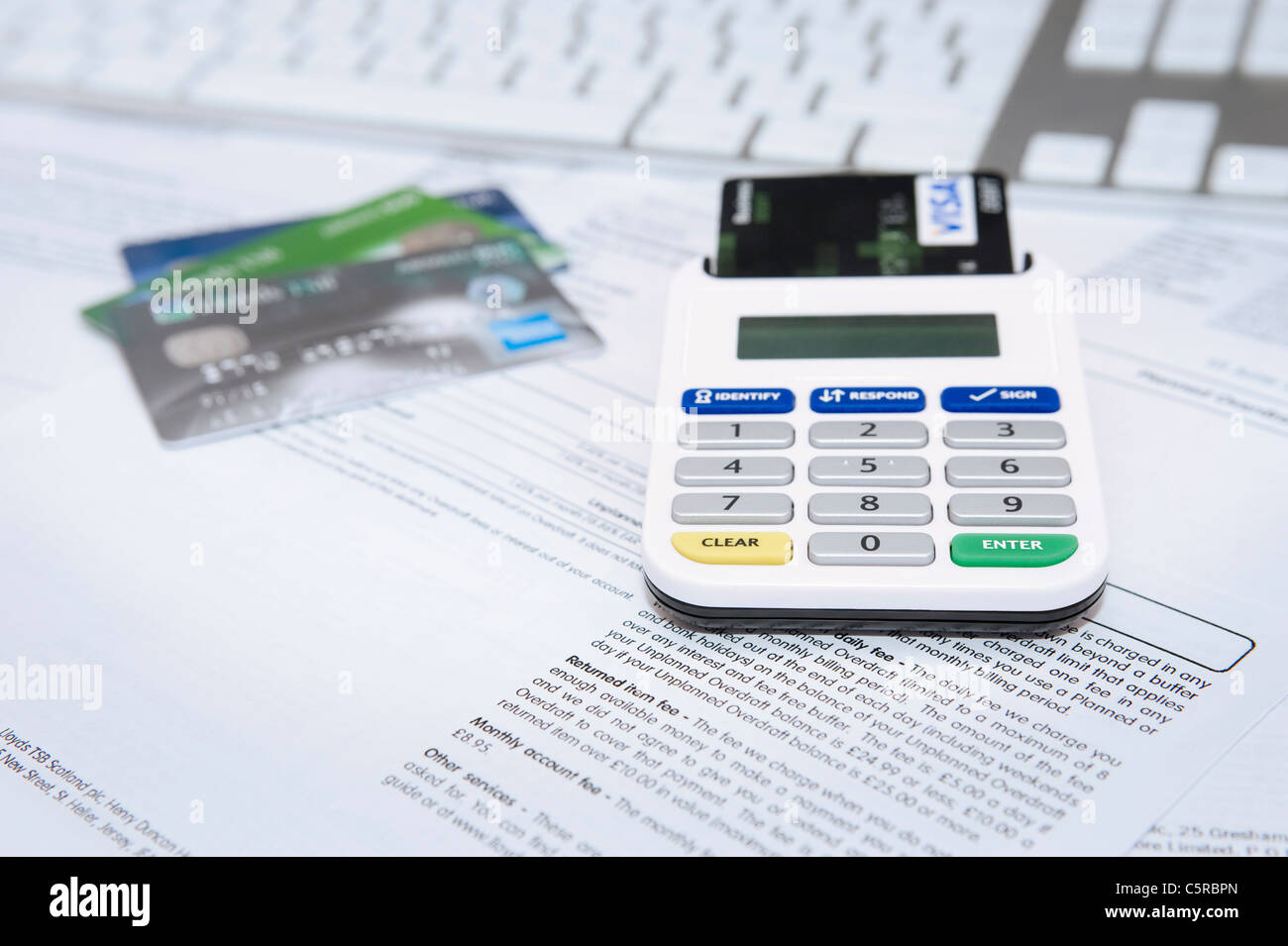 Banca Internet Card Reader con carta inserita seduto sugli estratti conto bancari con altre carte di credito e la tastiera in background Foto Stock