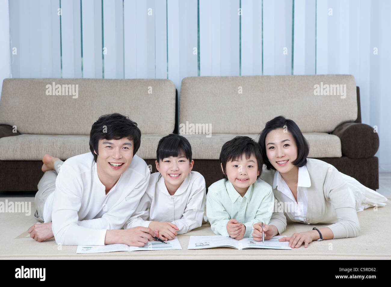 Una famiglia che giacciono sul loro stomaco sul pavimento Foto Stock