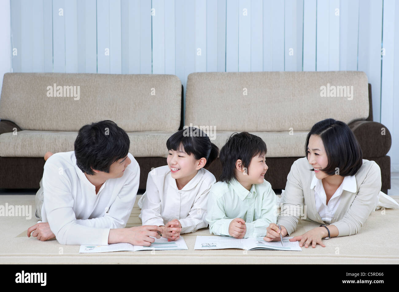 Una famiglia che giacciono sul loro stomaco cercando ogni altro Foto Stock