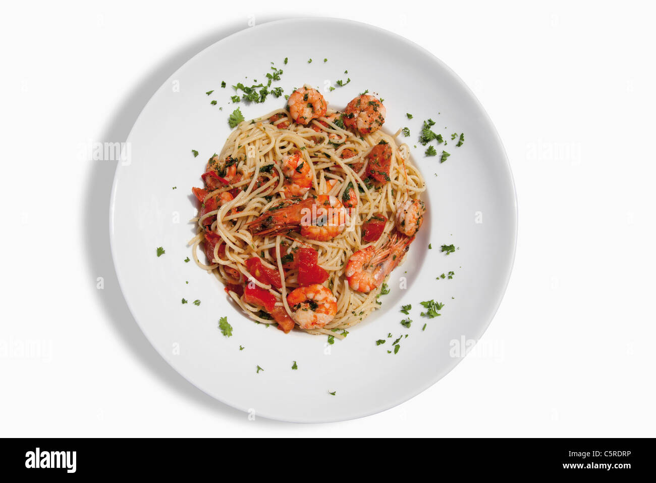 Close up di spaghetti con scampis fritti in olio aromatizzato al peperoncino, estratto di pomodoro e le erbe contro uno sfondo bianco Foto Stock