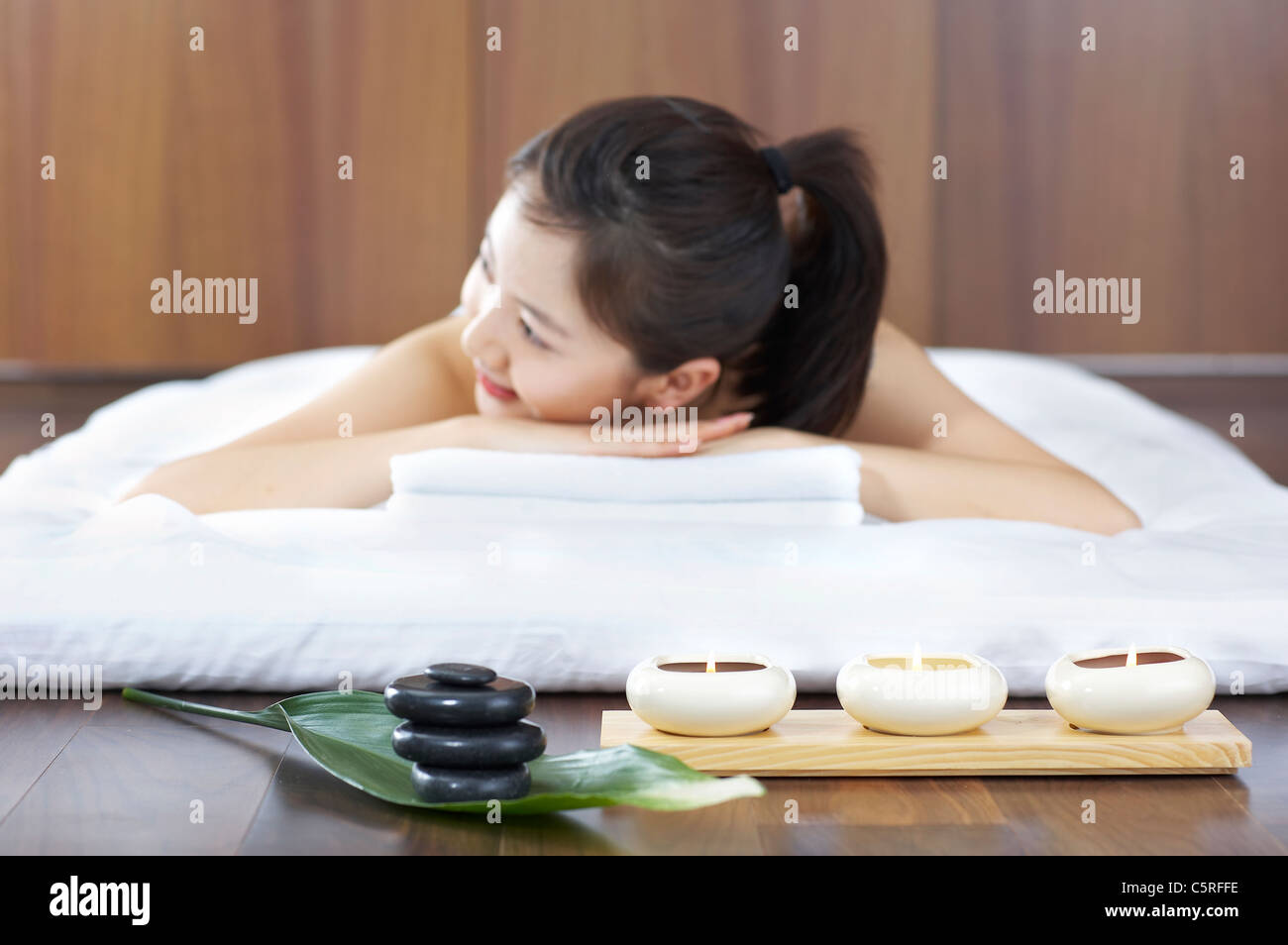 Una donna sdraiata con candele e pietre di terapia Foto Stock