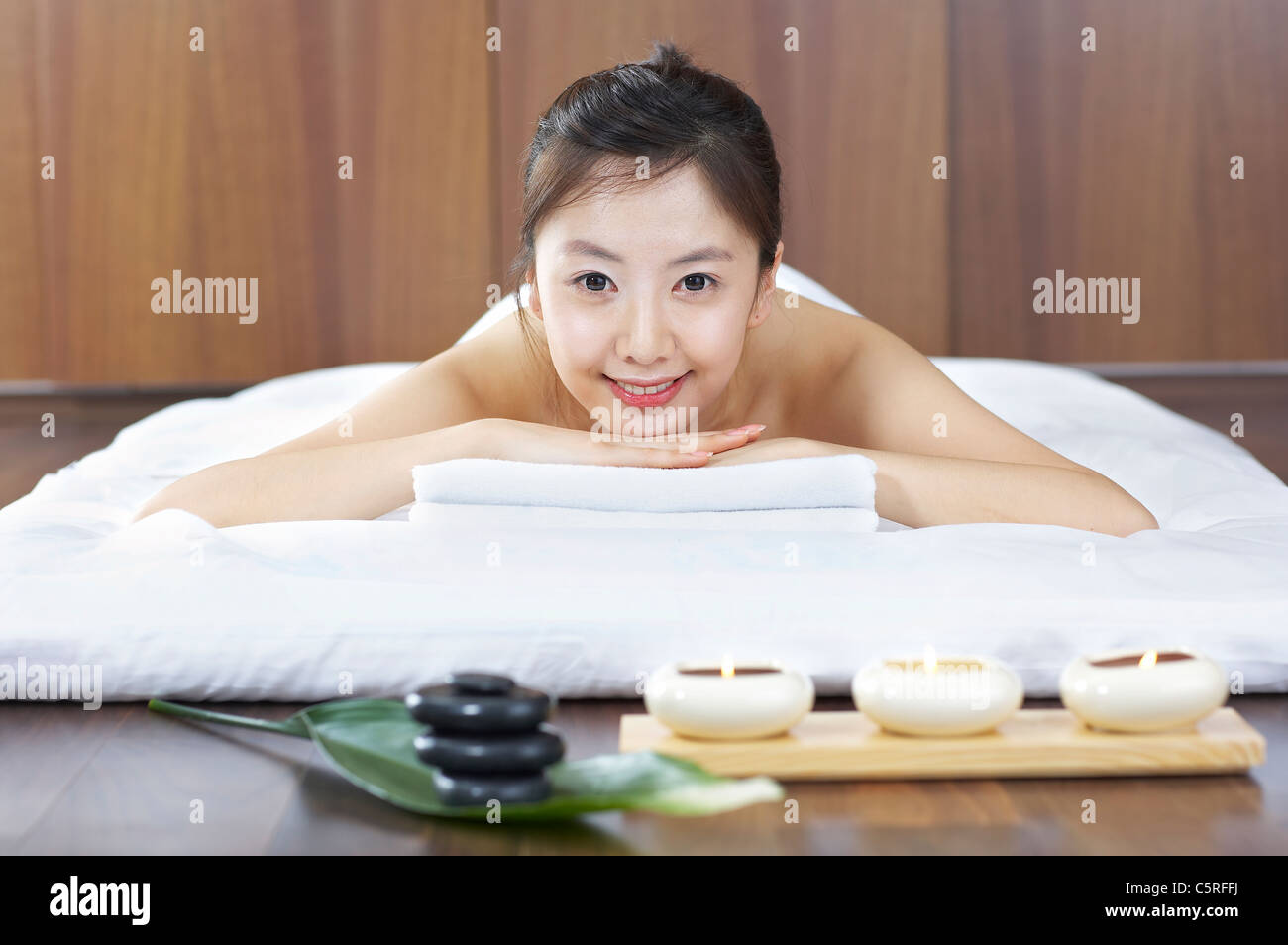 Una donna sdraiata con candele e pietre di terapia Foto Stock