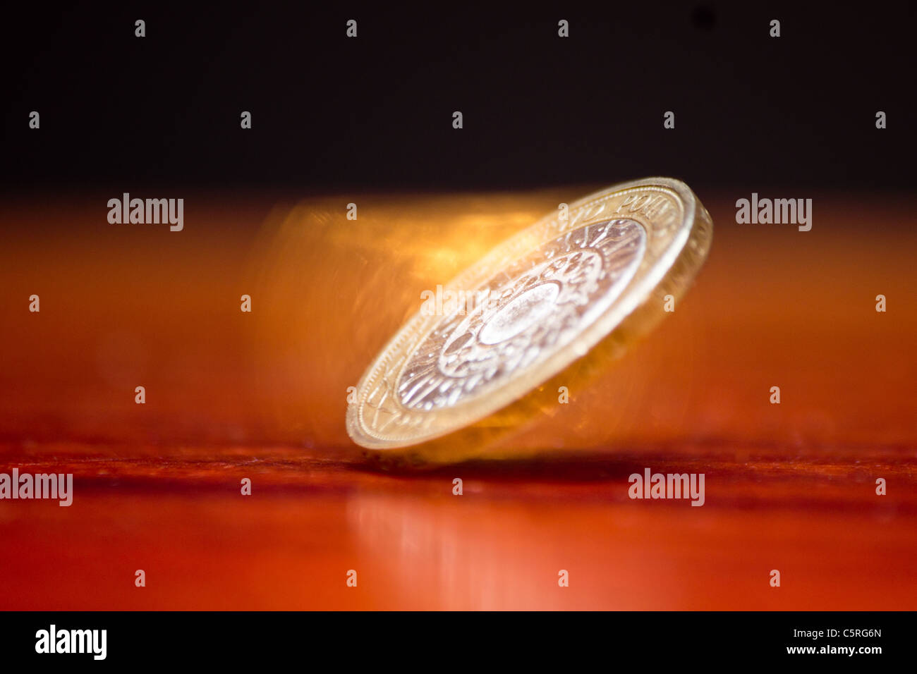 La filatura due pound coin su un tavolo di legno con uno sfondo nero Foto Stock