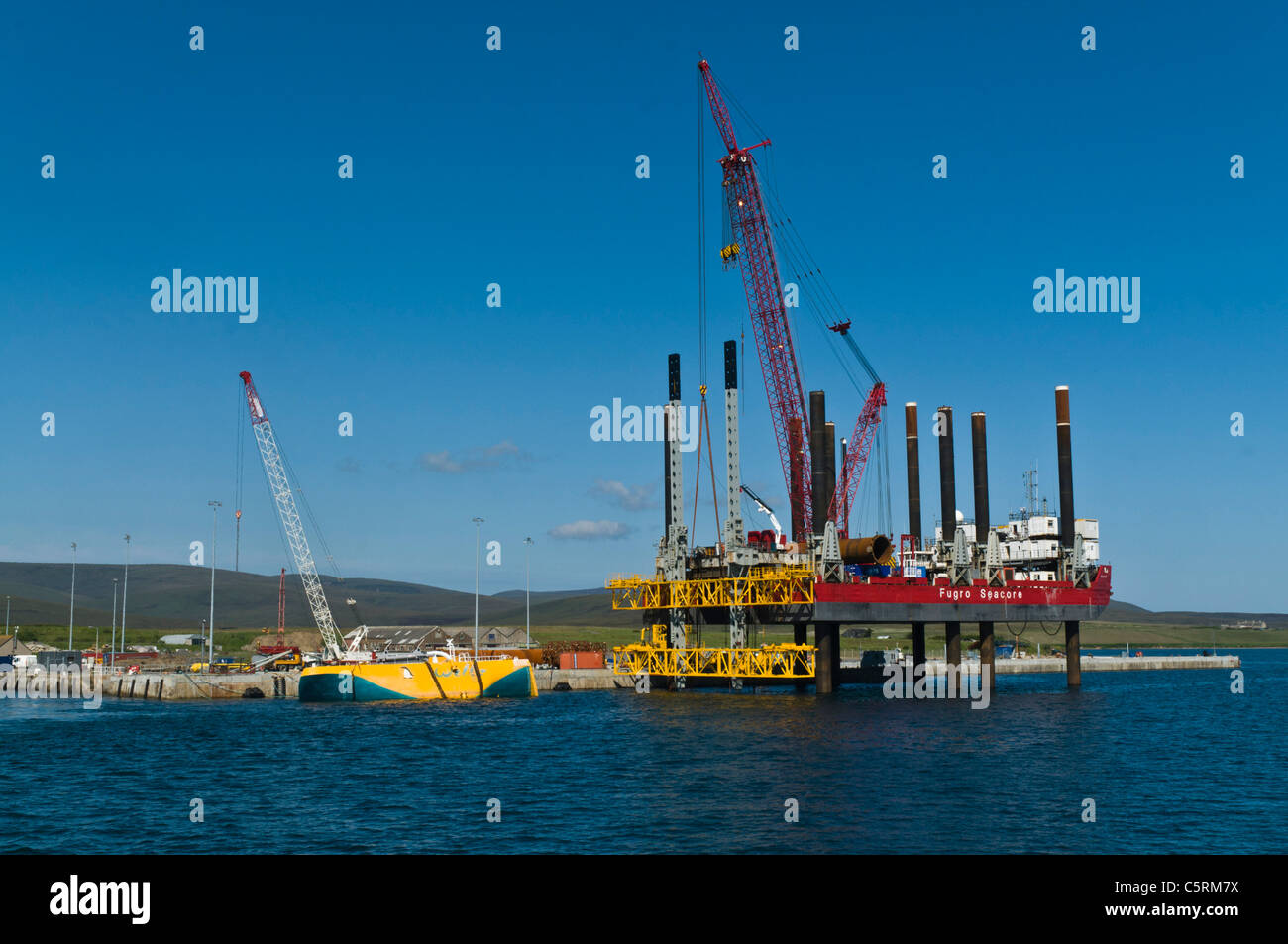 Dh Lyness Pier HOY ORKNEY Fugro Seacore piattaforma di posizionamento rig e giallo Wellos Penguin fonti rinnovabili Foto Stock