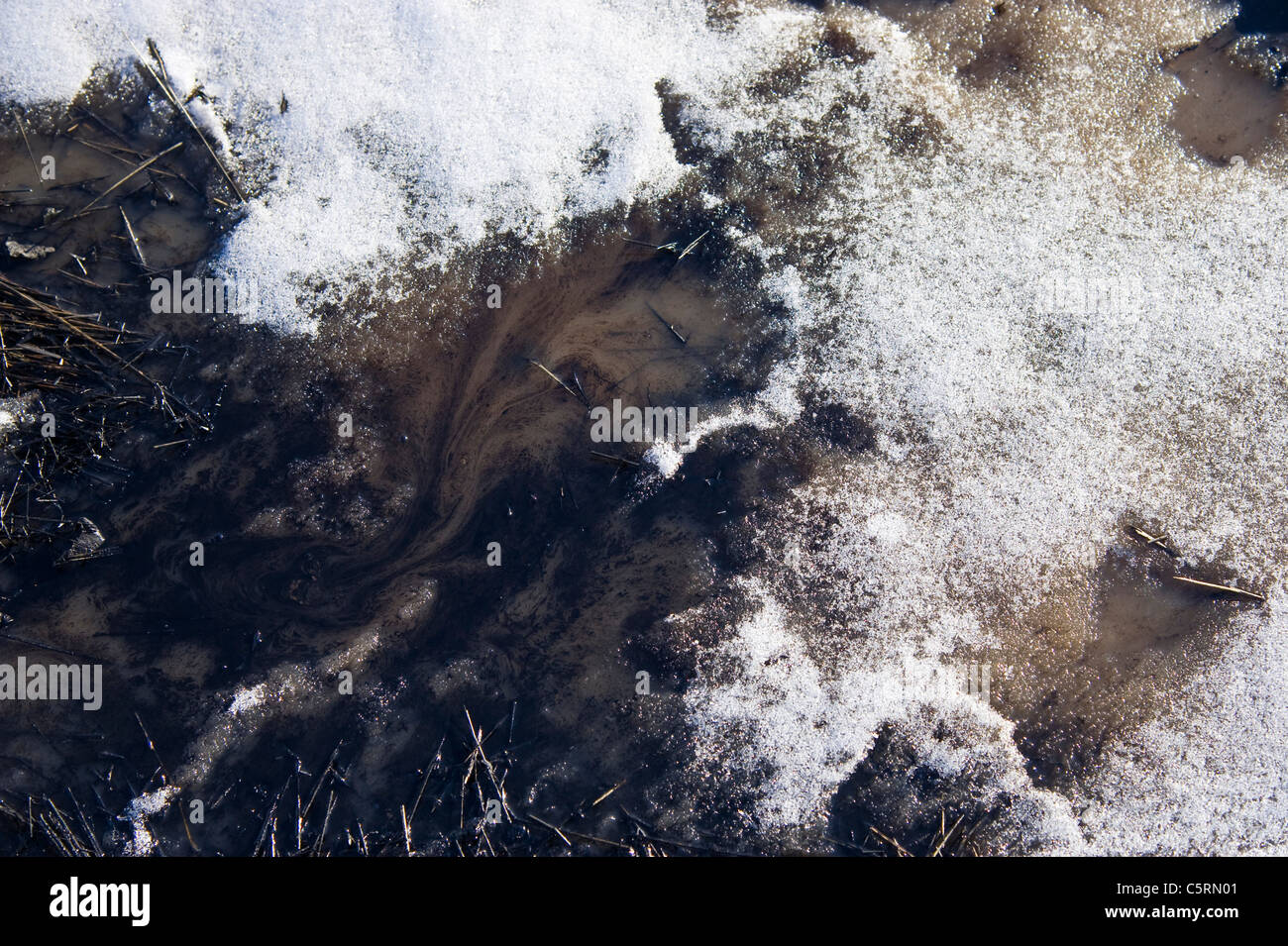 Una chiusura di immagine utilizzato olio sparso sul terreno e diffondere nella vicina pozza d'acqua. Foto Stock