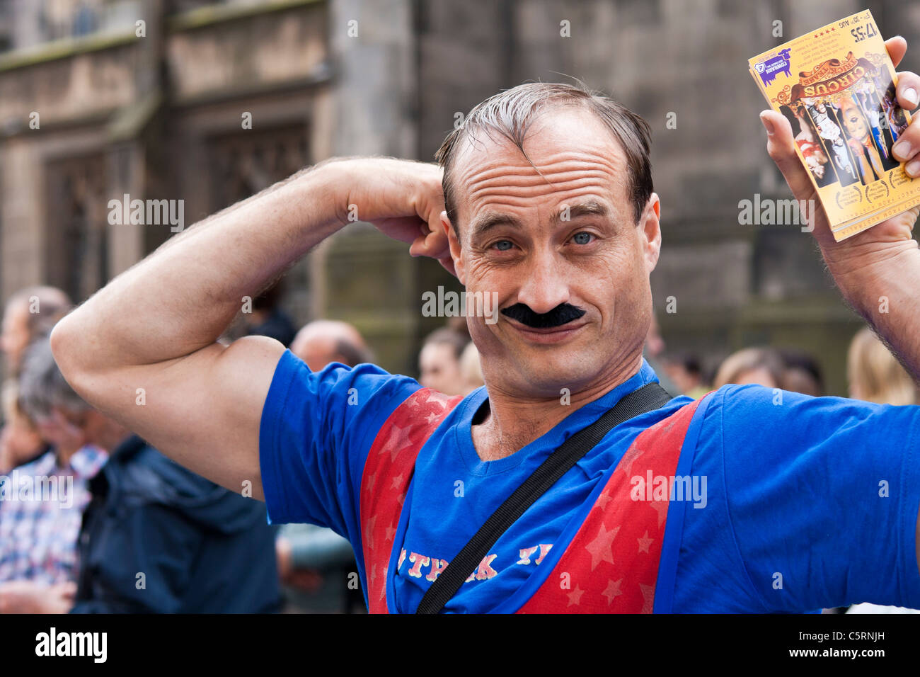 Un uomo muscoloso vestito come un circo uomo forte su Edinburgh Royal Mile, promuovendo il suo spettacolo del Fringe Festival Foto Stock