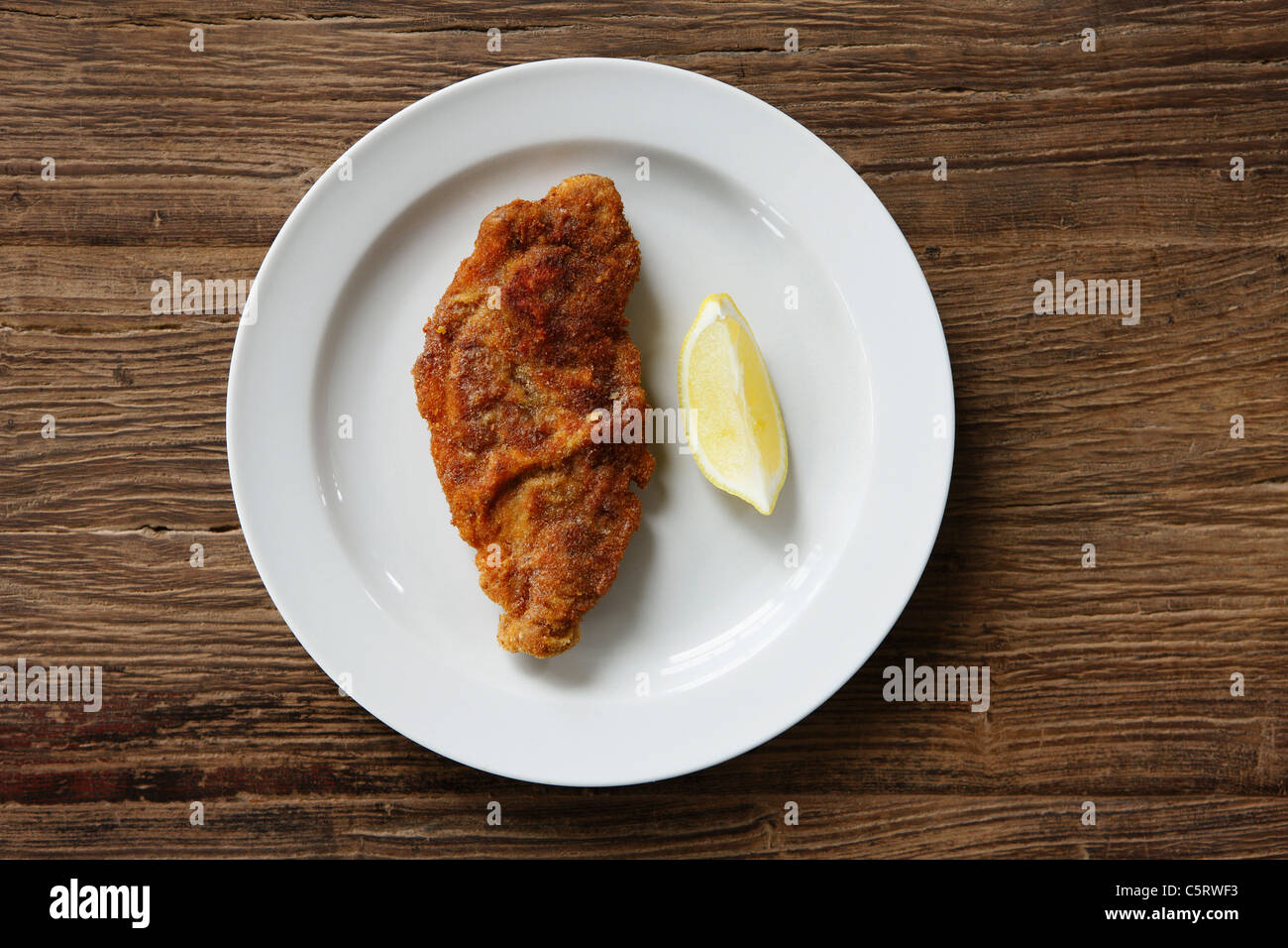 La Wiener Schnitzel con fettina di limone su sfondo di legno, close up Foto Stock