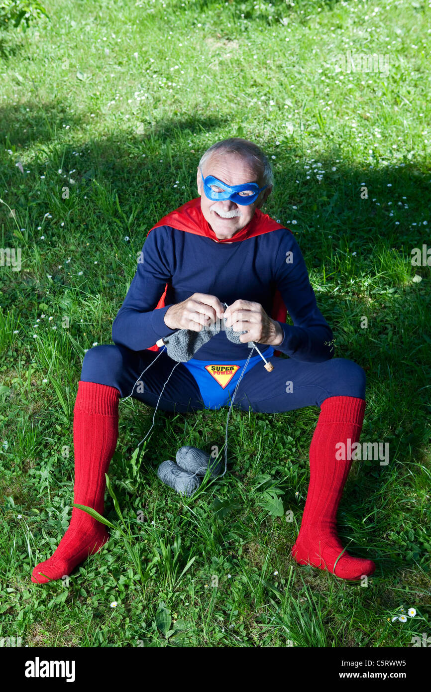 Austria, Burgenland, Senior uomo in superman costume seduto sull'erba e di  lavorazione a maglia Foto stock - Alamy