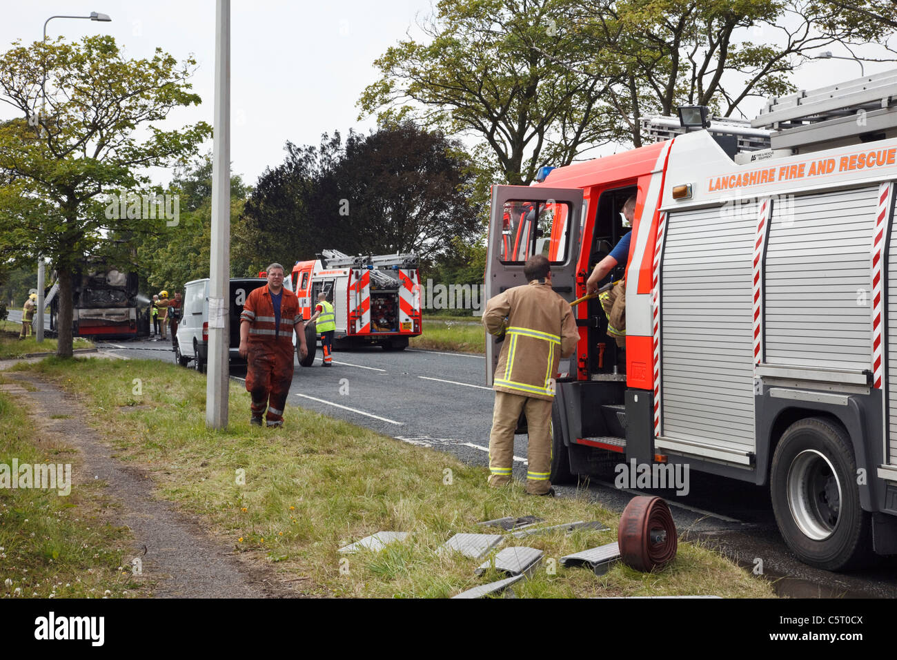 Lancashire, Inghilterra, Regno Unito. Motore Fire e equipaggio frequentando un incidente di spegnere l'incendio su un bus di masterizzazione Foto Stock