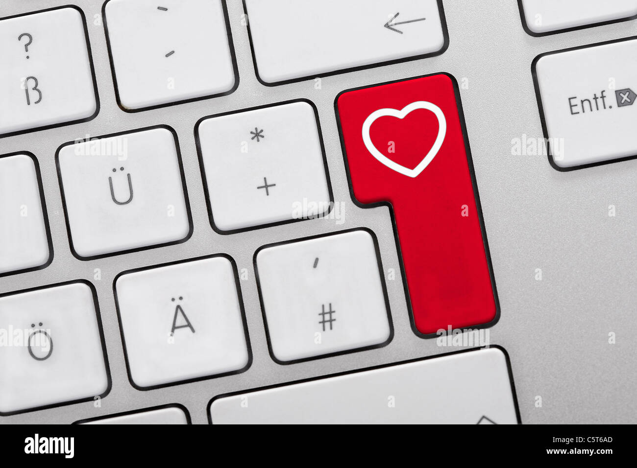 Close up di chiavi di computer con cuore simbolo sul tasto rosso Foto Stock