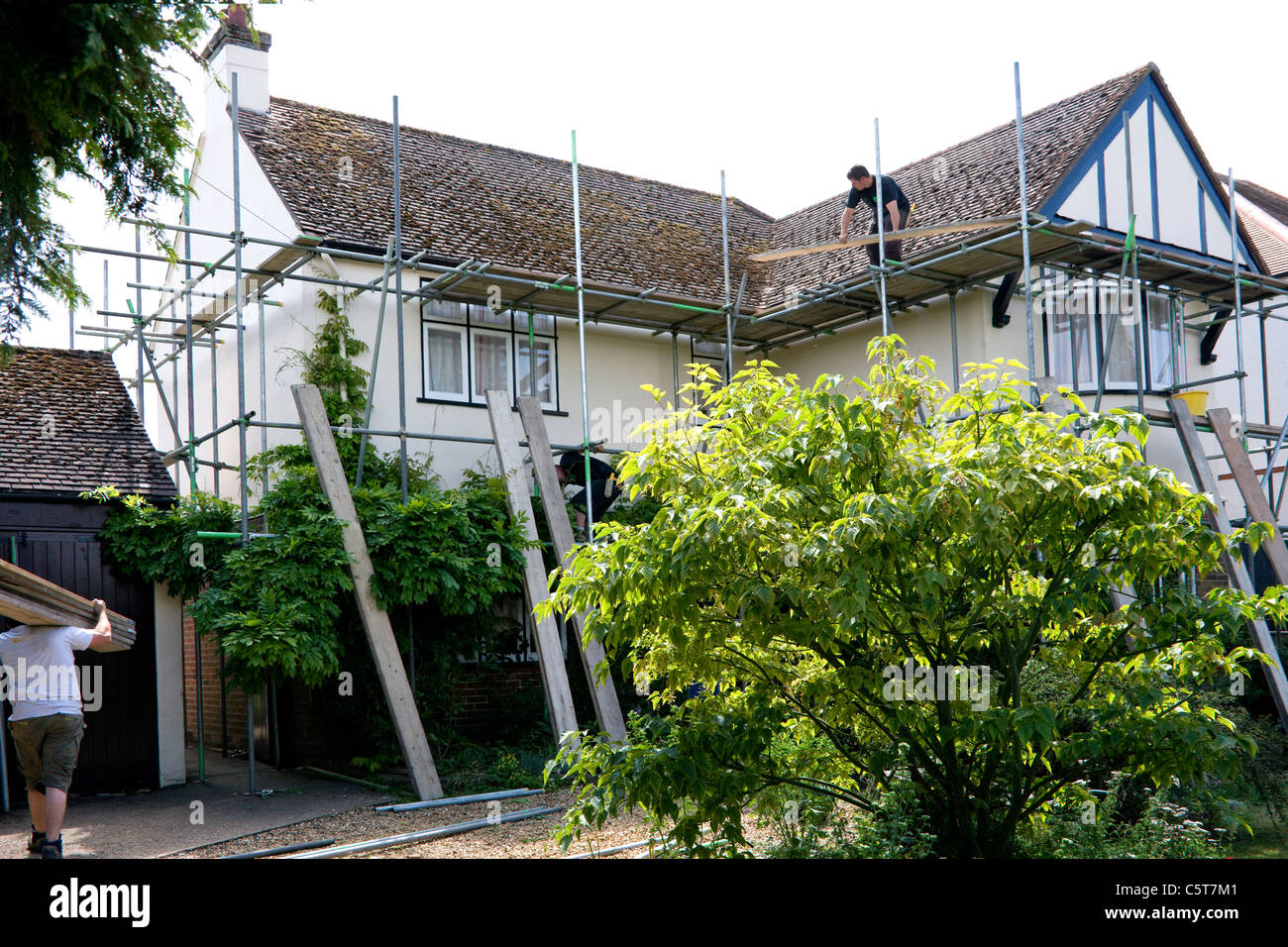 Fase finale di impalcatura erezione, assi essendo prevista per la passerella intorno al tetto della casa. Foto Stock