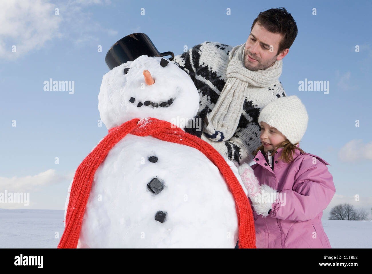 In Germania, in Baviera, Monaco di Baviera, padre e figlia (6-7) facendo un pupazzo di neve, ritratto Foto Stock
