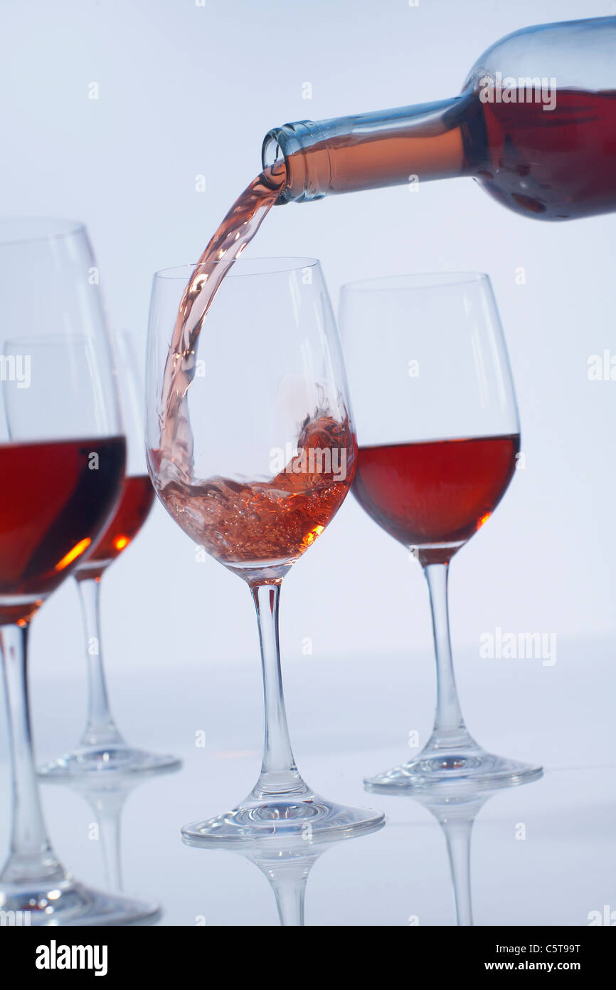 Versando il vino rosato in rosa bicchieri di vino Foto Stock